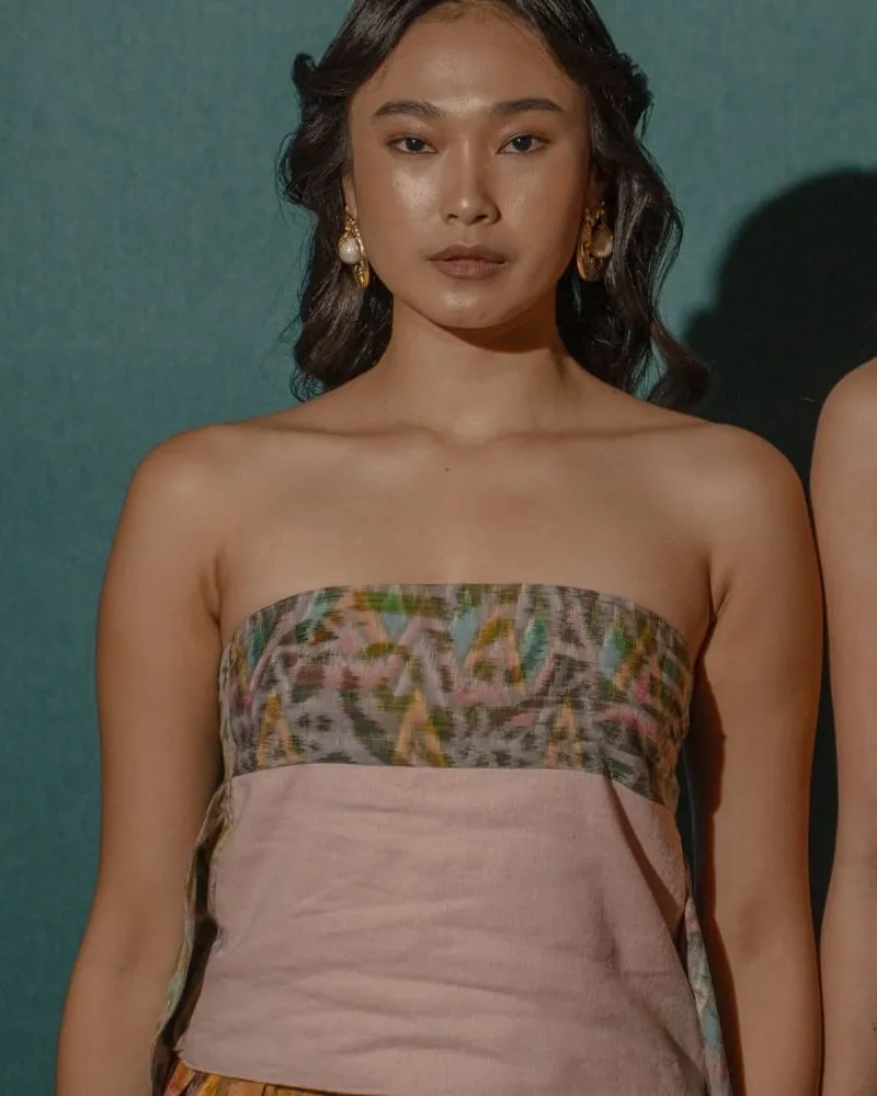 Model wearing a strapless bustier with a woven ikat band over a dusty-pink linen panel.