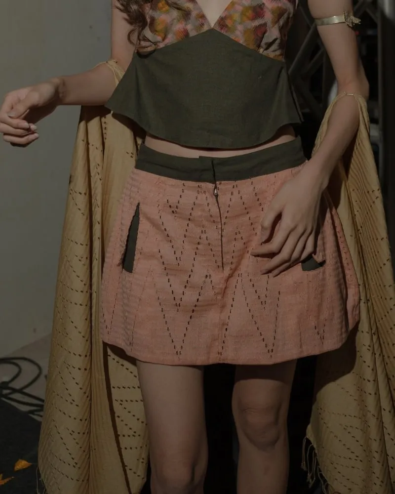 Model wearing an A-line mini skirt in pink zigzag-woven cloth with an olive waistband.